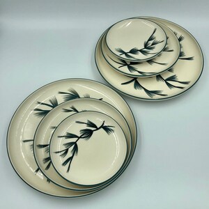 May include: Set of five white ceramic plates with a green pine branch design. The plates are nested together in two stacks.