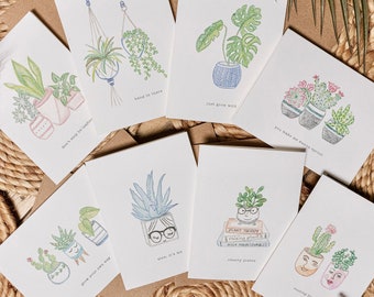 May include: Set of ten greeting cards featuring illustrated plants in pots with humorous sayings. The cards are white with black text and are printed on a textured paper. The sayings include "Don't stop be-leafin", "Hang in there", "Just grow wild", "You make me wanna sprout", "Grow your own way", "Aloe, it's me", "Plant therapy", "Raising plants", "High maintenance", "Smarty plants", and "Rooting for you".