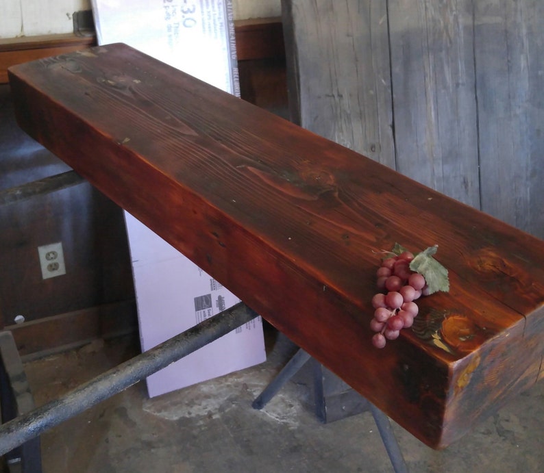 May include: A dark red wooden shelf with a cluster of red grapes on top. The shelf is made of reclaimed wood and has a rustic look.