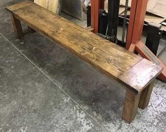May include: A rustic wooden bench with a natural brown finish. The bench has a simple design with straight legs and a wide, flat top.