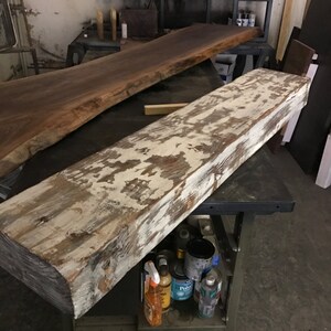 May include: A weathered wooden shelf with a whitewashed finish. The shelf is sitting on a metal workbench with various paint cans and cleaning supplies.