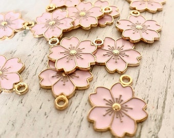 May include: A collection of pink and gold metal flower charms with a delicate design. The charms have a loop for attaching to jewelry or other crafts.