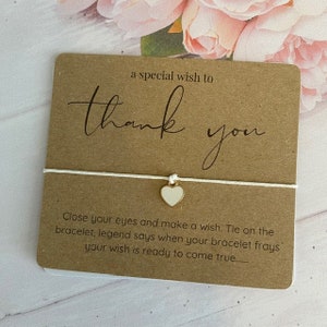 May include: A brown card with the text "a special wish to thank you" and a white string bracelet with a white heart charm. The card also includes the text "Close your eyes and make a wish. Tie on the bracelet, legend says when your bracelet frays your wish is ready to come true..."