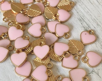 May include: A collection of pink heart-shaped charms with gold accents. The charms have a delicate, feminine design and are perfect for adding a touch of sparkle to jewelry or crafts.