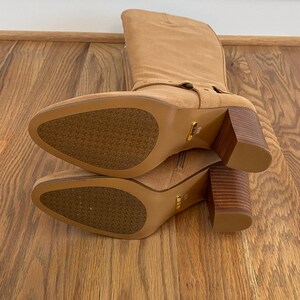 Puede incluir: Un par de botas de ca&ntilde;a alta de ante marr&oacute;n con tac&oacute;n de bloque y cremallera en el interior de la bota. Las botas tienen una tira decorativa con tachuelas doradas en la parte superior del pie.