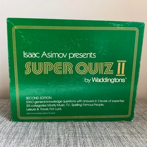 May include: A green box with gold lettering for a board game called "Super Quiz II" by Waddingtons. The box features a second edition label and lists 5760 general knowledge questions with answers in 3 levels of expertise. Six categories are listed: Mostly Music, T.V., Spelling, Famous People, Leisure & Travel, and Pot Luck.