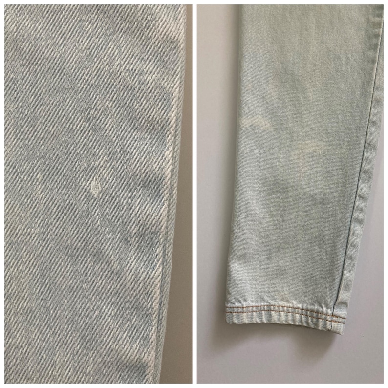 May include: Close-up of light blue denim jeans. The fabric shows a subtle texture with a small imperfection. The hem is finished with brown stitching. The jeans appear to be pre-worn.