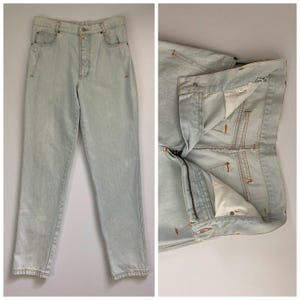 May include: Light wash denim jeans with a button fly and five-pocket design. The jeans have a straight leg cut and are shown both fully assembled and with the fly unzipped, revealing the interior construction.