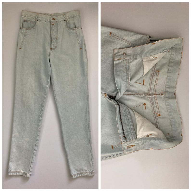 May include: Light wash denim jeans with a button fly and five-pocket design. The jeans have a straight leg cut and are shown both fully assembled and with the fly unzipped, revealing the interior construction.