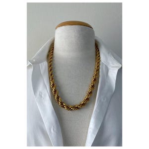 May include: A gold rope chain necklace on a white shirt mannequin.