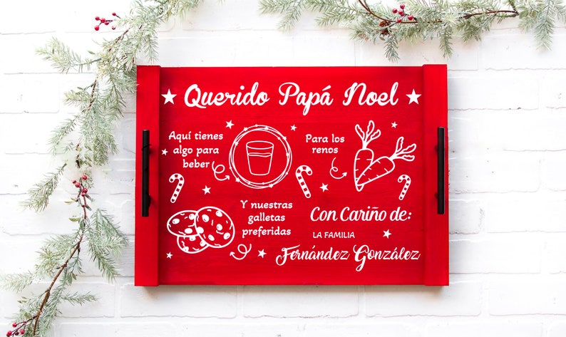 K&ouml;nnte beinhalten: Rotes Holztablett mit wei&szlig;er Aufschrift "Querido Pap&aacute; Noel" und einer Liste mit Artikeln f&uuml;r den Weihnachtsmann und die Rentiere. Die Liste enth&auml;lt ein Glas Milch, Kekse und Karotten. Das Tablett hat auch schwarze Griffe.