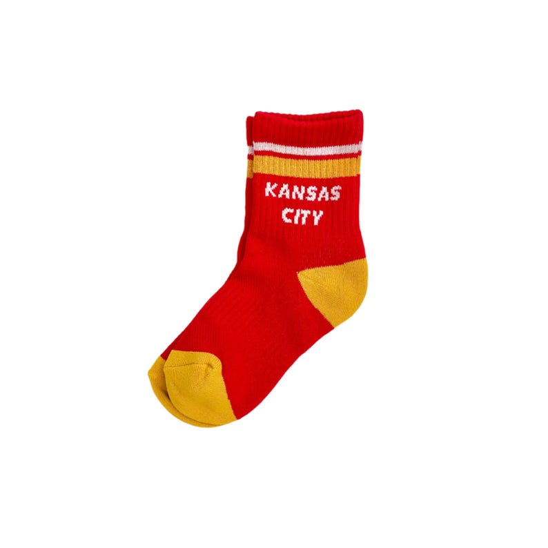 May include: Red and gold sock with the text "KANSAS CITY" in white. The sock has a red body with gold accents on the heel and toe. The top of the sock features gold and white stripes.