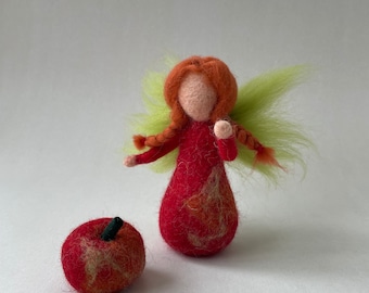 May include: A felt fairy doll with red hair, a red dress with orange leaf designs, and green wings. The fairy is holding a red felt apple.