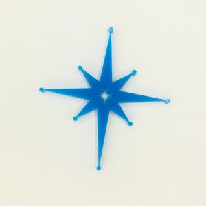 May include: A blue star-shaped ornament with a smaller star cut out in the center. The ornament is made of a translucent material and has a shiny finish.