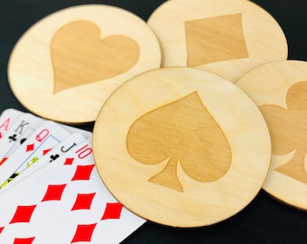 May include: Four wooden coasters with different playing card suits: heart, diamond, spade, and club. The coasters are light brown and have a natural wood finish.