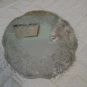 May include: A silver-plated serving tray with a scalloped edge and an intricate floral design.
