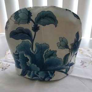 May include: White teapot cover with a blue floral pattern. The cover has a rounded top and a flat bottom.
