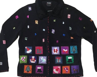 Op de afbeelding: Zwarte cardigan met een feestelijk kerstontwerp. De trui heeft verschillende kleurrijke geborduurde kerstpictogrammen, waaronder de kerstman, cadeaus en een kerstboom. De trui heeft een nep bontkraag en een knoopsluiting.