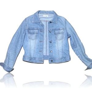 May include: A light blue denim jacket with a button closure and two front pockets.