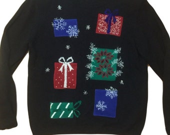 Op de afbeelding: Een zwarte kersttrui met een feestelijk ontwerp van kleurrijke cadeautjes en sneeuwvlokken.