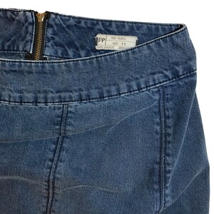 Pu&ograve; includere: Un paio di jeans blu denim con zip e un'etichetta Free People che dice "Free People" e "Taglia: W6".