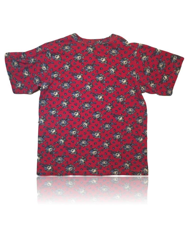 May include: A red short-sleeved t-shirt with a floral pattern. The flowers are blue and white.
