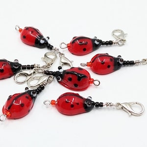 May include: Six red and black ladybug stitch markers with silver clasps and black beads.