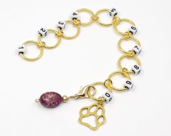 Jumbo, numbered, gold tone row counter, with paw print charm and purple semi precious stone progress keeper.