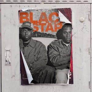 Könnte beinhalten: Ein Schwarzweiß-Poster mit dem Text "Black Star" in orangefarbenen Buchstaben. Zwei Männer sind auf dem Poster abgebildet, einer trägt eine schwarze Jacke und der andere eine blaue Jacke. Das Poster ist an einer Metalloberfläche befestigt.