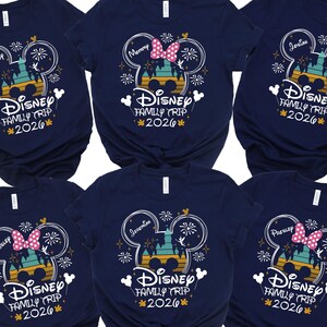 May include: Navy blue t-shirts with a Disney theme. Each shirt features a Mickey Mouse head design with the text "Disney Family Trip 2026". Some shirts have names like "Mommy" and "Josim" printed above the design.