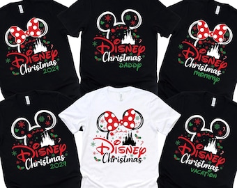 Könnte beinhalten: Sechs schwarze und weiße T-Shirts mit einem Disney-Weihnachtsmotiv. Die Shirts zeigen Mickey-Maus-Ohren, eine rote Schleife und den Text "Disney Christmas" mit einem Jahr oder einem Spruch.