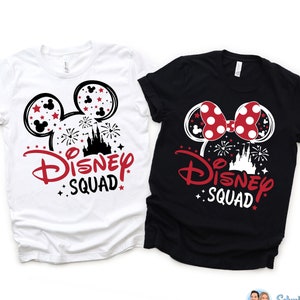 Puede incluir: Dos camisetas blancas con gr&aacute;ficos negros y rojos. La camiseta de la izquierda presenta orejas de Mickey Mouse con un texto rojo "Disney Squad". La camiseta de la derecha presenta orejas de Minnie Mouse con un lazo rojo y un texto rojo "Disney Squad".