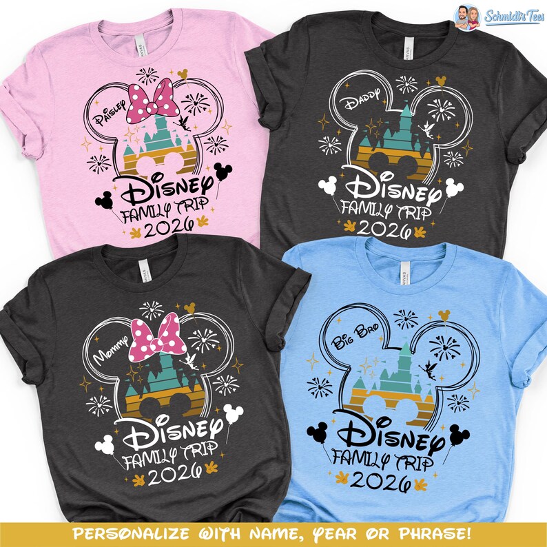 May include: Four short-sleeved t-shirts in pink, charcoal, and blue, each featuring a Disney-themed design. The design includes a Mickey Mouse head outline, a castle, fireworks, and the text "Disney Family Trip 2026".