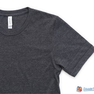 Puede incluir: Camiseta gris oscuro con cuello redondo y mangas cortas. La camiseta tiene una etiqueta que dice "CANVAS". La tela tiene una textura jaspeada. La camiseta es talla L.