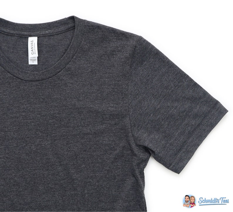 Puede incluir: Camiseta gris oscuro con cuello redondo y mangas cortas. La camiseta tiene una etiqueta que dice "CANVAS". La tela tiene una textura jaspeada. La camiseta es talla L.