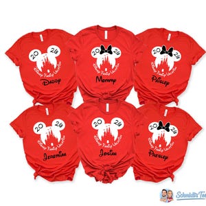 Puede incluir: Seis camisetas de manga corta de color rojo brillante con una silueta blanca de la cabeza de Mickey Mouse que contiene un castillo, el texto 2026 y Disney Family Vacation. Algunas incluyen un lazo negro y nombres personalizados como Daddy, Mommy, Paisley, Jeremiah, Josiah y Presley.