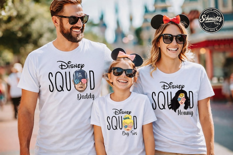 May include: White t-shirts with the text "Disney Squad" and character graphics. The shirts feature "Daddy", "Mommy", and "Big Sis" designations. The characters are Captain America, Wonder Woman, and Tinkerbell.