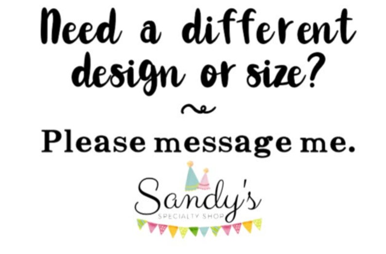 May include: Text that reads "Need a different design or size? Please message me. Sandy's SPECIALTY SHOP" with a wavy line above the word "Please". The text is in black font on a white background. There are two party hats above the word "Sandy's" and a string of colorful flags below the word "SHOP".