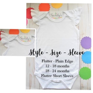 May include: White baby bodysuit with flutter sleeves. The bodysuit has the text "Sandy's" on the front. The text "Style - Size - Sleeve" is printed below the bodysuit. The text "Flutter - Plain Edge" is printed below the text "Style - Size - Sleeve". The text "12-18 months" is printed below the text "Flutter - Plain Edge". The text "18-24 months" is printed below the text "12-18 months". The text "Flutter Short Sleeve" is printed below the text "18-24 months".