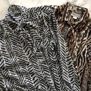 May include: Two long-sleeved blouses with animal print patterns. One blouse has a black and white chevron pattern, the other has a brown, black, and white zebra and leopard print. The blouse with the zebra and leopard print has a label that says "Expos&eacute;".