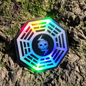 May include: A holographic sticker with a black and white pixelated skull and lightning bolt inside a Dharma Initiative symbol.