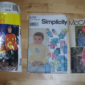 May include: Three sewing patterns for costumes. The first pattern is for a pumpkin costume, the second is for a baby outfit, and the third is for a fairy costume. The patterns are from McCall's and Simplicity.