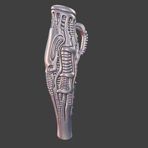 May include: A silver-colored, stylized vase with a handle. The vase has a unique, textured design with organic, biomechanical elements. The overall shape is elongated and tapers towards the base, with a detailed, sculpted surface.