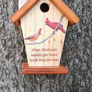 May include: Wooden birdhouse with a pitched roof and a small chimney. The front features a painted design of two red cardinals perched on a branch, with the text "When Cardinals appear, you know loved ones are near."
