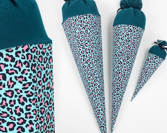 Könnte beinhalten: Drei Schultüten mit teal- und pinkfarbenem Leopardenmuster in verschiedenen Größen. Die Oberseite jeder Tüte ist aus einfarbigem teal-Stoff, gerafft und gebunden. Der Leopardenprint befindet sich auf hellblauem Hintergrund.