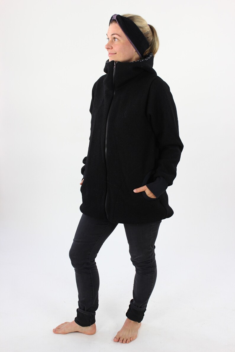May include: A black fleece jacket with a high collar and a zipper closure. The jacket has a relaxed fit and is worn by a person with black jeans and a black headband.