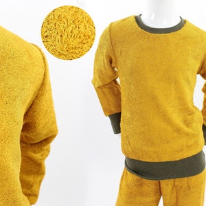 Może przedstawiać: Żółta bluza z długim rękawem, okrągłym dekoltem w serek i dopasowanymi spodniami. Bluza ma zielony ściągacz wokół szyi i mankietów.