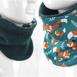 Peut inclure: Un tour de cou réversible avec un côté en polaire turquoise et un côté en coton turquoise avec un motif répété de renards orange.