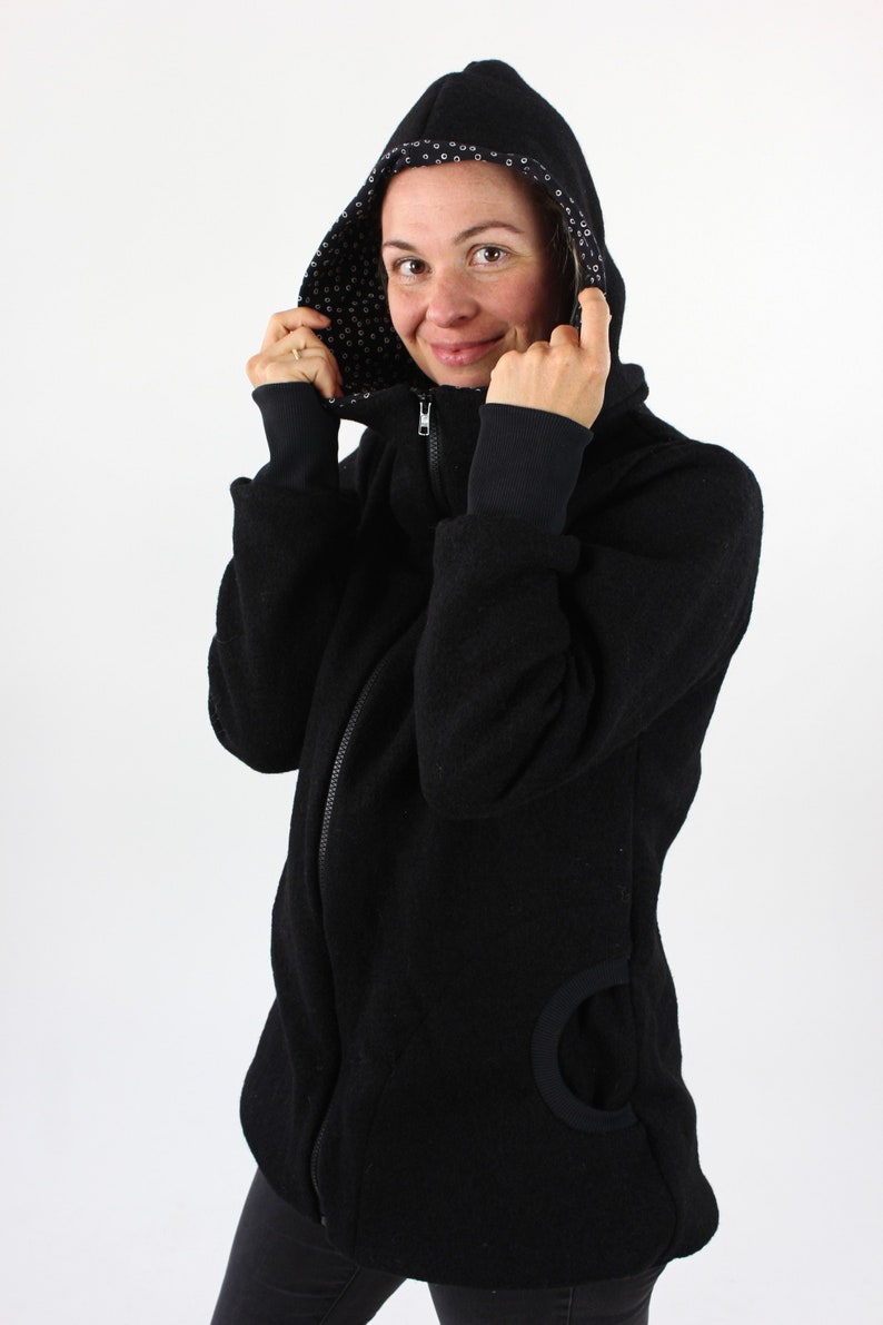 May include: A black hooded jacket with a zipper closure and a black and white patterned lining. The jacket has a large pocket on the left side.
