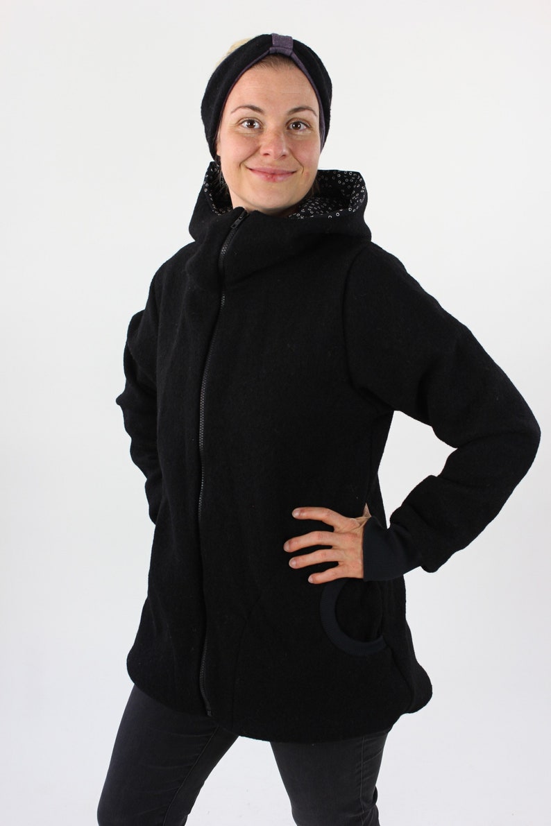 May include: A black hooded jacket with a zipper closure and a small pocket on the left side. The jacket has a black and white patterned lining around the hood.